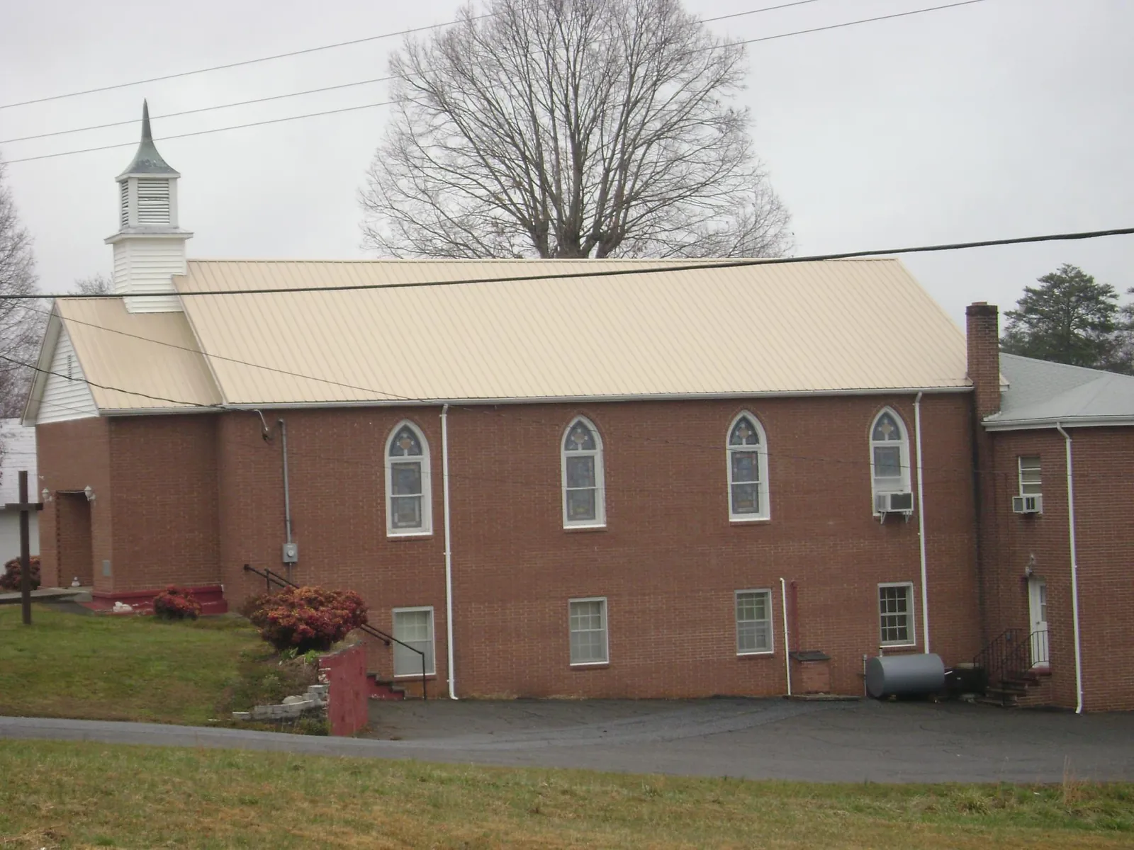 New tan metal roof on a brick church with a white steeple in Spencer